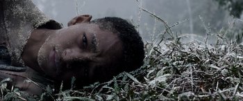 Movie still from “After Earth” (2013), directed by M. Night Shyamalan – A man laying in the grass looking at the camera; Close Up shot, Low angle