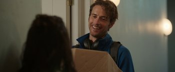Movie still from “Afterlife of the Party” (2021), directed by Stephen Herek – A man wearing headphones smiles at a woman in a blue jacket; Close Up shot, Over the shoulder angle