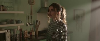 Movie still from “Afterlife of the Party” (2021), directed by Stephen Herek – A woman in a silver dress standing in front of a stove; Close Up shot, Over the shoulder angle
