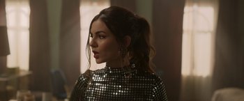 Movie still from “Afterlife of the Party” (2021), directed by Stephen Herek – A woman in a silver dress looking to her left; Close Up shot, Over the shoulder angle