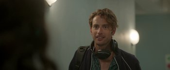 Movie still from “Afterlife of the Party” (2021), directed by Stephen Herek – A man with headphones on looking at the camera; Close Up shot, Over the shoulder angle