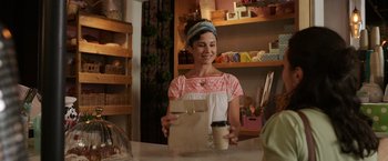 Movie still from “Afterlife of the Party” (2021), directed by Stephen Herek – A woman holding a paper bag and a cup of coffee; Medium shot, Over the shoulder angle