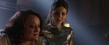 Movie still from “Afterlife of the Party” (2021), directed by Stephen Herek – A woman in a silver dress standing next to another woman; Close Up shot, Over the shoulder angle