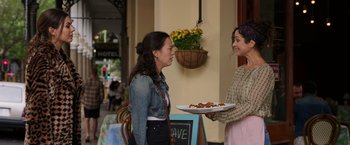 Movie still from “Afterlife of the Party” (2021), directed by Stephen Herek – A woman holding a tray of food talking to another woman; Medium shot, Over the shoulder angle