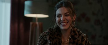 Movie still from “Afterlife of the Party” (2021), directed by Stephen Herek – A woman in a leopard print jacket smiling for the camera; Close Up shot, Over the shoulder angle