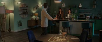 Movie still from “Afterlife of the Party” (2021), directed by Stephen Herek – A group of people sitting at a table in a room; Wide shot, High angle