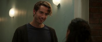 Movie still from “Afterlife of the Party” (2021), directed by Stephen Herek – A young man smiling at the camera while standing next to a woman; Close Up shot, Over the shoulder angle