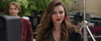 Movie still from “Afterlife of the Party” (2021), directed by Stephen Herek – A beautiful woman with long brown hair wearing pink earrings; Close Up shot, Over the shoulder angle