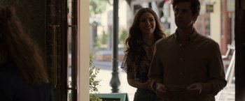 Movie still from “Afterlife of the Party” (2021), directed by Stephen Herek – A young woman smiles while standing next to a man; Medium shot, Over the shoulder angle