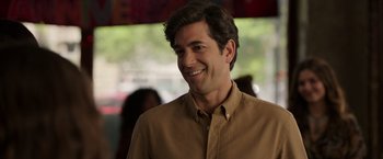 Movie still from “Afterlife of the Party” (2021), directed by Stephen Herek – A person wearing a brown shirt smiling; Close Up shot, Over the shoulder angle