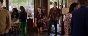 Movie still from “Afterlife of the Party” (2021), directed by Stephen Herek – A man and a woman holding hands while standing in front of a building; Wide shot, Over the shoulder angle