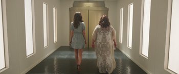 Movie still from “Afterlife of the Party” (2021), directed by Stephen Herek – Two women are walking down the hall of a building; Wide shot, Low angle