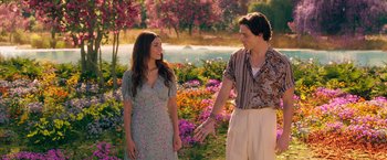 Movie still from “Afterlife of the Party” (2021), directed by Stephen Herek – A man and a woman standing next to each other in front of flowers; Medium shot, Over the shoulder angle