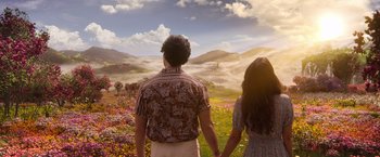 Movie still from “Afterlife of the Party” (2021), directed by Stephen Herek – A man and a woman holding hands while standing in a field of flowers; Medium shot, High angle