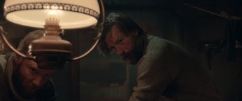 Movie still from “Against the Ice” (2022), directed by Peter Flinth – A man with long hair and a beard is looking at the camera; Medium shot, Over the shoulder angle