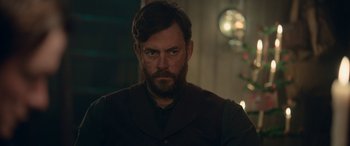 Movie still from “Against the Ice” (2022), directed by Peter Flinth – A man with a goatee and a beard stares at the camera; Close Up shot, Over the shoulder angle