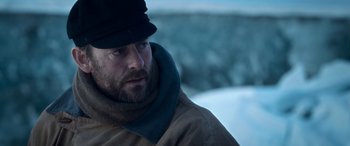 Movie still from “Against the Ice” (2022), directed by Peter Flinth – A person wearing a jacket and hat; Close Up shot, Over the shoulder angle