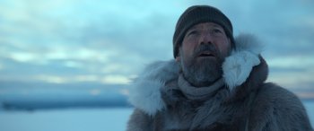 Movie still from “Against the Ice” (2022), directed by Peter Flinth – A man with a beard wearing a fur coat and a hat; Close Up shot, Over the shoulder angle