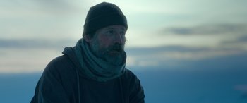 Movie still from “Against the Ice” (2022), directed by Peter Flinth – A man with a beard wearing a hat and a scarf; Close Up shot, Low angle