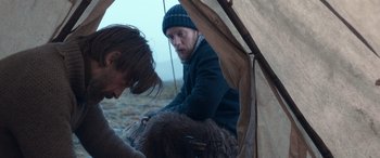 Movie still from “Against the Ice” (2022), directed by Peter Flinth – A man and a woman sitting in front of a tent; Medium shot, Over the shoulder angle