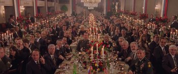 Movie still from “Air Force One” (1997), directed by Wolfgang Petersen – A group of people sitting around a dinner table; Extreme Wide shot, High angle