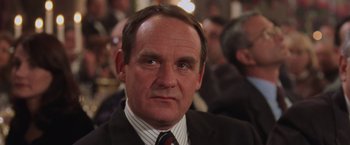 Movie still from “Air Force One” (1997), directed by Wolfgang Petersen – A man in a suit and tie looking at the camera; Close Up shot, Low angle