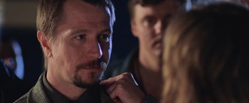 Movie still from “Air Force One” (1997), directed by Wolfgang Petersen – A man with a beard is adjusting his tie; Close Up shot, Over the shoulder angle