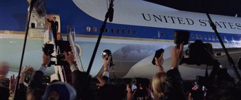 Movie still from “Air Force One” (1997), directed by Wolfgang Petersen – A crowd of people taking pictures of a large airplane; Wide shot, Low angle
