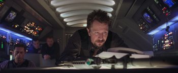 Movie still from “Air Force One” (1997), directed by Wolfgang Petersen – A man sitting at a table looking at a piece of paper on top of a desk; Close Up shot, Low angle