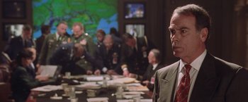 Movie still from “Air Force One” (1997), directed by Wolfgang Petersen – A group of people sitting around a table; Close Up shot, Over the shoulder angle