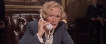 Movie still from “Air Force One” (1997), directed by Wolfgang Petersen – A woman talking on a phone while sitting in a chair; Close Up shot, Low angle