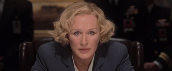 Movie still from “Air Force One” (1997), directed by Wolfgang Petersen – A person wearing a suit and tie; Close Up shot, Over the shoulder angle