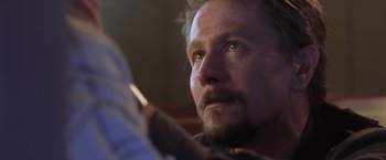 Movie still from “Air Force One” (1997), directed by Wolfgang Petersen – A man with a beard looking up; Close Up shot, Low angle