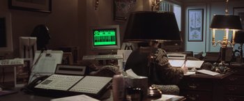 Movie still from “Air Force One” (1997), directed by Wolfgang Petersen – A computer monitor sitting on top of a desk; Medium shot, Over the shoulder angle