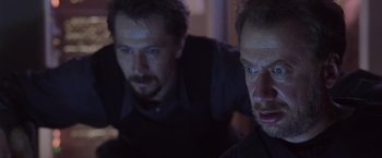 Movie still from “Air Force One” (1997), directed by Wolfgang Petersen – A couple of men standing next to each other in a room; Close Up shot, Low angle