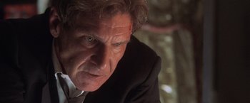 Movie still from “Air Force One” (1997), directed by Wolfgang Petersen – An older man in a suit looking at the camera; Close Up shot, Low angle