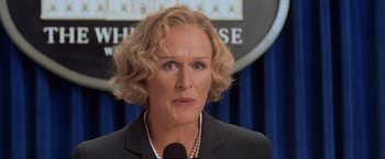 Movie still from “Air Force One” (1997), directed by Wolfgang Petersen – A person wearing a suit and tie; Close Up shot, Over the shoulder angle