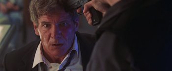 Movie still from “Air Force One” (1997), directed by Wolfgang Petersen – A person holding a gun near another person; Close Up shot, Over the shoulder angle