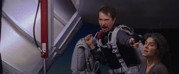 Movie still from “Air Force One” (1997), directed by Wolfgang Petersen – A man with a backpack is jumping off a plane; Medium shot, Low angle