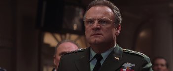 Movie still from “Air Force One” (1997), directed by Wolfgang Petersen – A person wearing glasses and a uniform; Close Up shot, Low angle