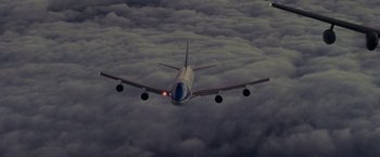 Movie still from “Air Force One” (1997), directed by Wolfgang Petersen – An airplane is flying through the clouds in the sky; Extreme Wide shot, Low angle