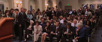 Movie still from “Air Force One” (1997), directed by Wolfgang Petersen – A group of people sitting in a large room; Wide shot, High angle