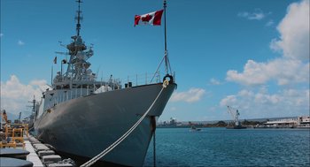 Movie still from “Aircraft Carrier: Guardian of the Seas” (2016), directed by Stephen Low – A canadian flag flies on the bow of a ship; Wide shot, Low angle