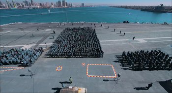 Movie still from “Aircraft Carrier: Guardian of the Seas” (2016), directed by Stephen Low – An aerial view of a large group of people on a boat; Extreme Wide shot, High angle
