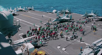 Movie still from “Aircraft Carrier: Guardian of the Seas” (2016), directed by Stephen Low – A large group of people on the deck of an aircraft carrier; Extreme Wide shot, High angle