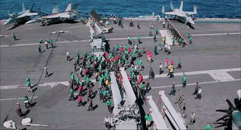 Movie still from “Aircraft Carrier: Guardian of the Seas” (2016), directed by Stephen Low – A large group of people on a deck of an aircraft carrier; Extreme Wide shot, High angle