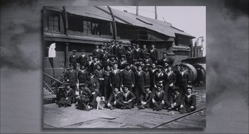 Movie still from “Aircraft Carrier: Guardian of the Seas” (2016), directed by Stephen Low – A group of men in uniform posing for a picture; Wide shot, High angle