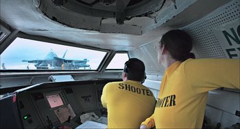 Movie still from “Aircraft Carrier: Guardian of the Seas” (2016), directed by Stephen Low – Two people are looking out the window of an aircraft; Medium shot, Over the shoulder angle