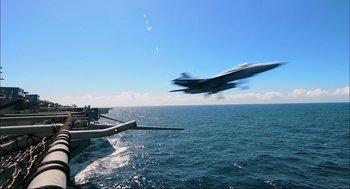Movie still from “Aircraft Carrier: Guardian of the Seas” (2016), directed by Stephen Low – An airplane is flying low over the ocean; Extreme Wide shot, Low angle