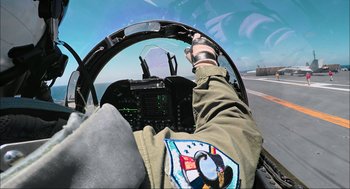 Movie still from “Aircraft Carrier: Guardian of the Seas” (2016), directed by Stephen Low – A person in the cockpit of an airplane; Medium shot, Overhead angle